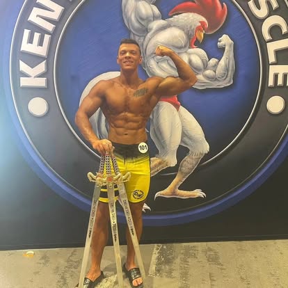 Legion athlete holding a trophy in front of a Kentucky Muscle backdrop